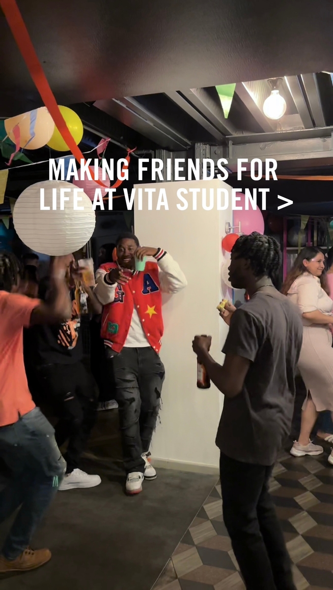 People dancing and holding drinks at a lively indoor party with colorful decorations. One person is pointing at the camera. The text reads, "MAKING FRIENDS FOR LIFE AT VITA STUDENT >".